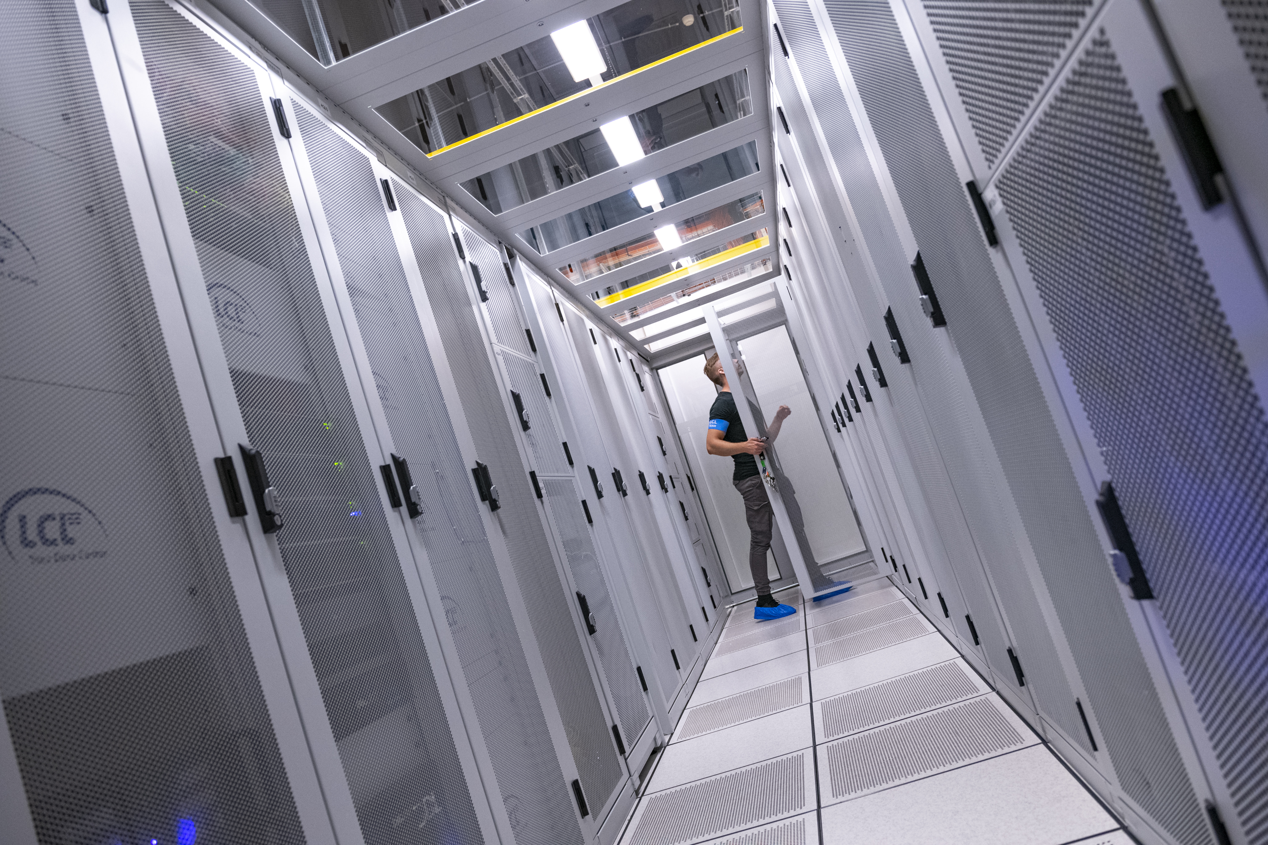 werknemer bekijkt de servers in de cold corridor van het datacenter