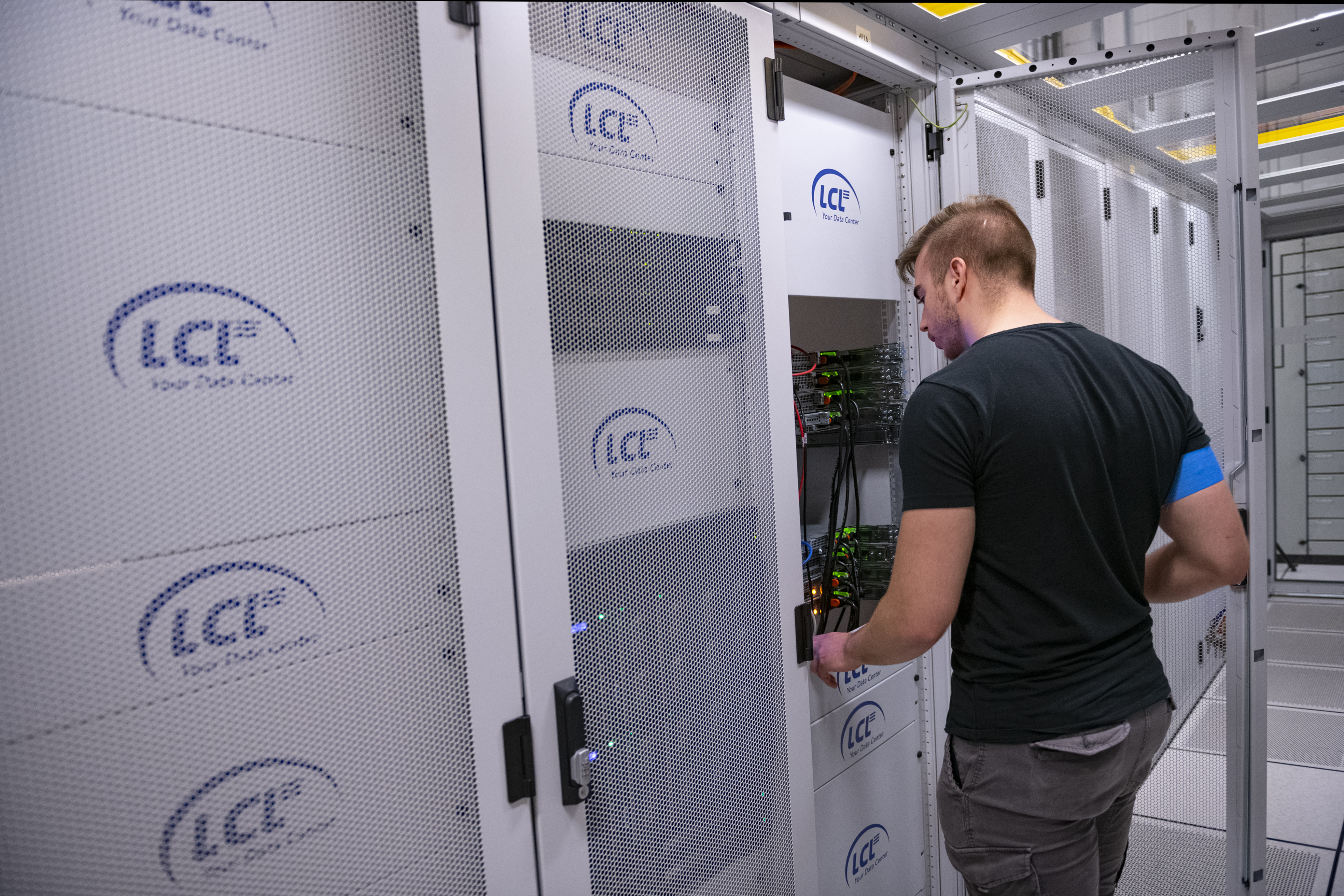 Werknemer controleert servers en racks in cold corridor datacenter